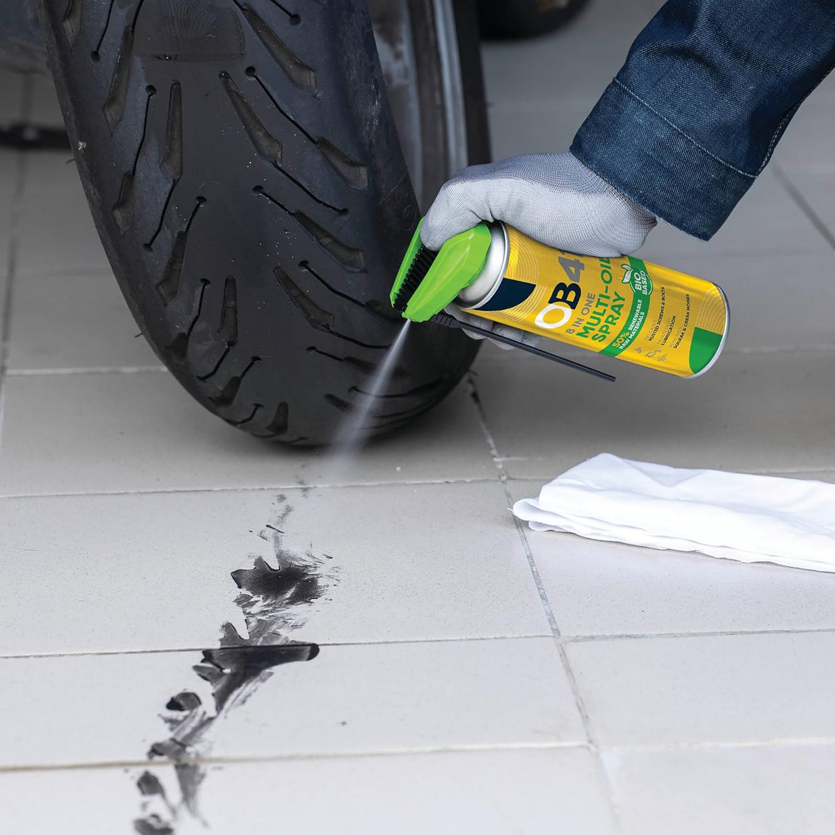 Person cleaning a tire mark with OB1 spray bottle on a tiled floor