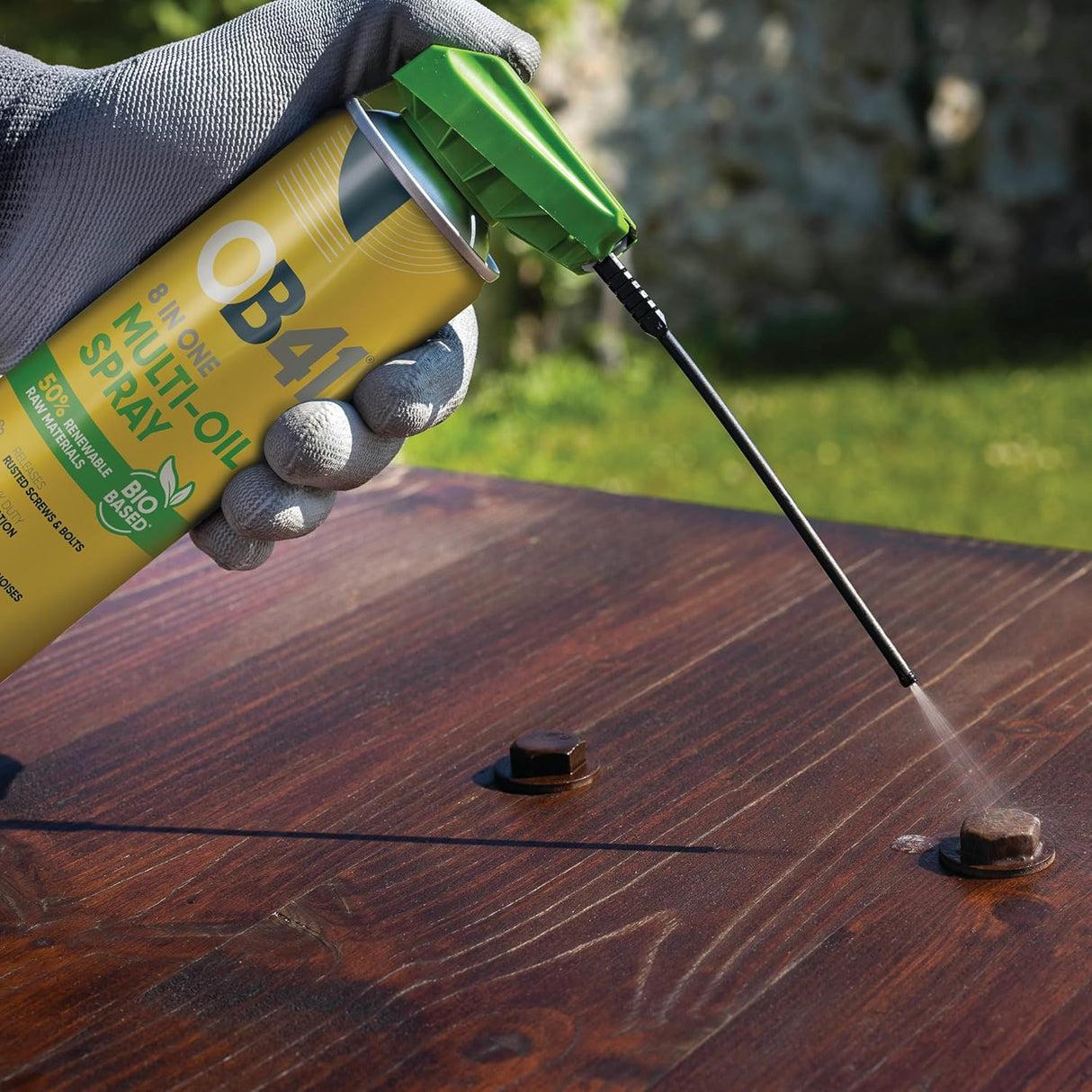 Person using a OB41 Multi-Oil spray can on a wooden surface outdoors.